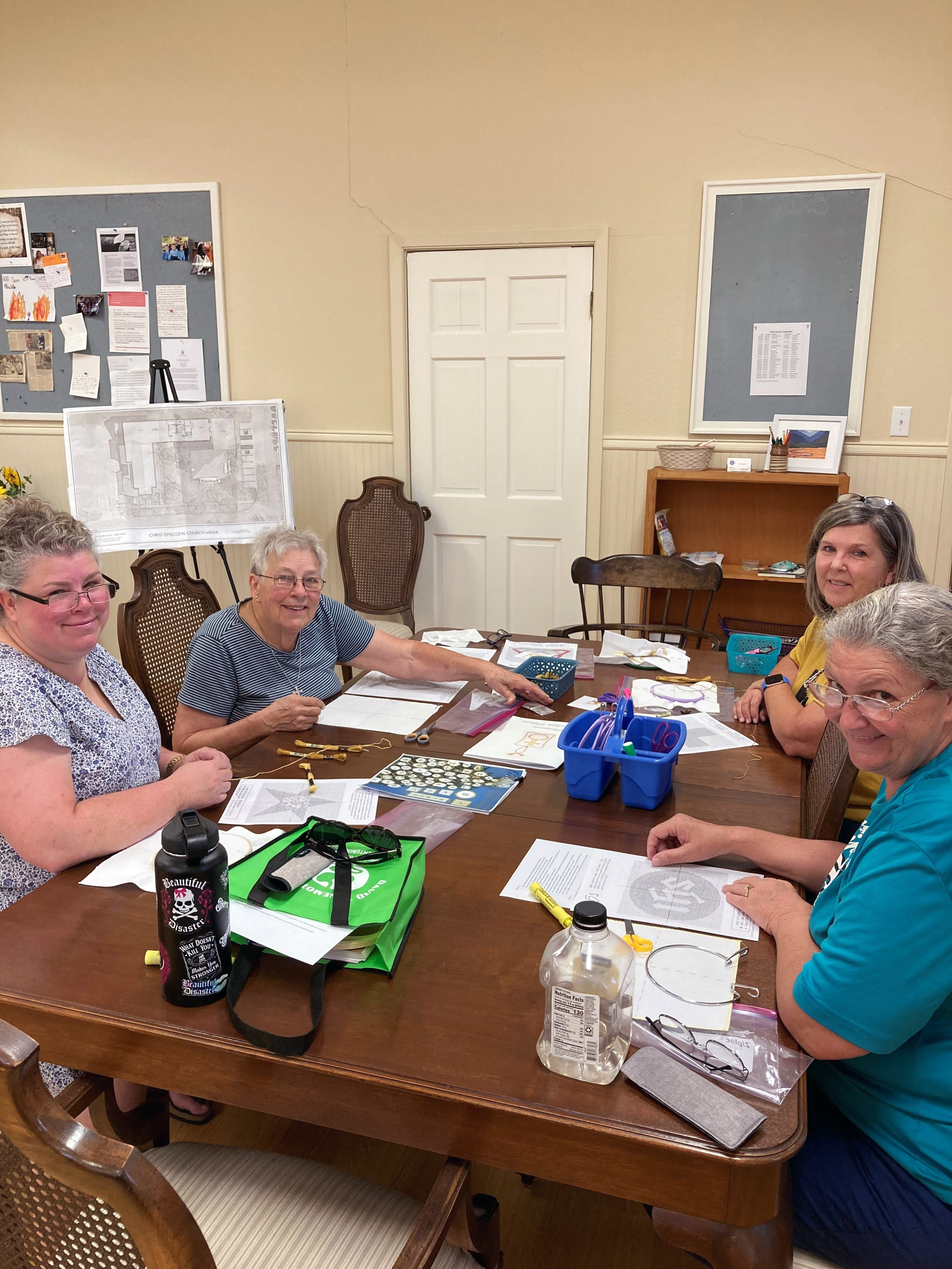 Photo of ladies sitting around table in the Parish Hall sewing new Chrismons